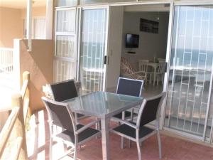 a glass table and chairs on a balcony at Camarque 28 in Umdloti