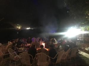 um grupo de pessoas sentadas em cadeiras à noite em Parhena Cottages Bella Naran em Nārān
