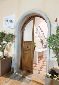einen Torbogen mit einer Holztür in einem Raum mit Topfpflanzen in der Unterkunft Talos Apartments in San Vito lo Capo