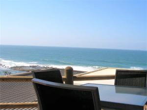 a table and chairs on a balcony overlooking the ocean at Camarque 28 in Umdloti
