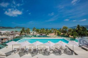 ein Pool mit weißen Sonnenschirmen und Stühlen und das Meer in der Unterkunft The Bloc Hotel Phuket - SHA Extra Plus in Patong Beach
