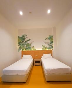 two beds in a room with white walls at Front One Green Boutique Hotel Abepura in Abepura