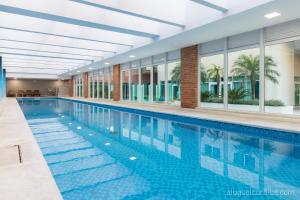 a swimming pool in a building with a large building at Luxuoso Apto Em Frente Ao Shopping Curitiba - Piscina, Academia e Sauna in Curitiba