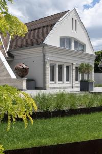 ein weißes Haus mit einem Rasenhof in der Unterkunft Hotel Bestseller in Kecskemét