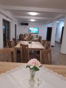 a dining room with a table with a vase of flowers at PENSIUNEA CAMELIA in Baia