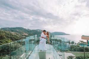 a bride and groom standing on top of a glass building at The Sea Galleri by Katathani - SHA Plus in Kata Beach