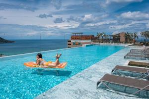 Una mujer está montando en una tabla de pádel naranja en una piscina en The Sea Galleri by Katathani - SHA Plus, en Kata Beach