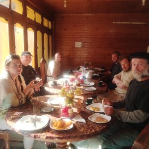 un grupo de personas sentadas alrededor de una mesa con comida en Foreigner Tourist Inn, en Tīsh