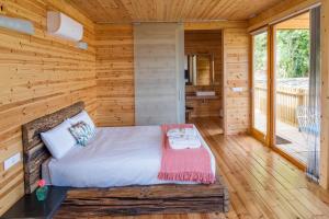 Dormitorio en cabaña de madera con cama y balcón en Cabanas de Canduas, en Cabana de Bergantiños