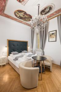 een slaapkamer met een bed, een tafel en een kroonluchter bij Apartments ART TEATRO in Rijeka