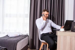 Lubhotel في لوبلين: رجل يجلس على مكتب يتحدث على الهاتف الخلوي