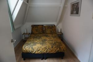 ZandhuizenにあるCharmantbuitenの小さなベッドルーム(ベッド1台付)が備わる屋根裏部屋です。