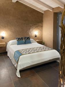 1 dormitorio con 1 cama blanca grande con almohadas azules en LUVIA ROOMS SPA, en Gonnesa