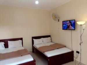 um quarto com duas camas e uma televisão na parede em Royal Park Hotel em Jinja