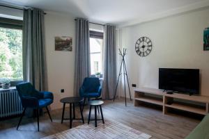 a living room with two blue chairs and a television at Apartma Ajda in Železniki