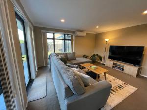 a living room with a couch and a flat screen tv at Your Happy place-Quiet area & Spa pool in Rotorua