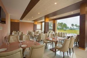 um restaurante com mesas e cadeiras e uma grande janela em Blue Serene Resort em Irimbranallūr