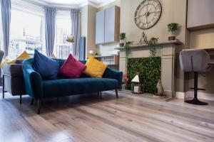 a living room with a blue couch with colorful pillows at Number 11 by the Warren Collection in Belfast