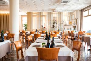 a dining room with tables and chairs with bottles at Hotel Souvenir in Lido di Jesolo