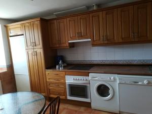 eine Küche mit einer Waschmaschine und einem Tisch in der Unterkunft Casa Rural Valdecorneja in Hoyorredondo