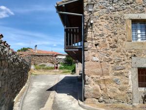 ein Steingebäude mit einem Balkon an einer Straße in der Unterkunft Casa Rural Valdecorneja in Hoyorredondo