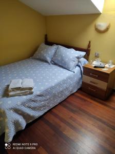 a bed with two pillows and a night stand at Pensión Rosa in Cabezón de la Sal