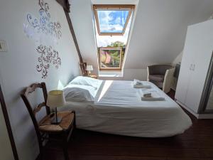 1 dormitorio con 1 cama, 1 silla y 1 ventana en VIEUX PASSAGE, Maison avec cour privée à 150 m du PORT et de la PLAGE, en Plouhinec