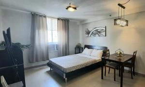 a bedroom with a bed and a table and a window at Cozy Studio near Beaches with NetFlix and Pool in Mactan