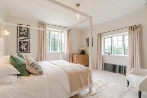 a white bedroom with a bed and a chair at Court Cottage in Stroud