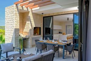 an outdoor dining room with a table and chairs at Luxury Beachfront Villa Raquel with Private Pool & Gym at Šolta, Croatia in Nečujam