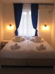 a bedroom with a large bed with blue curtains and a window at Evro set in Skopje