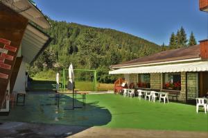 a house with a green yard with chairs and umbrellas at Hotel Cristallo in Folgaria