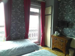 a bedroom with a bed and a window with red curtains at The Iverna in Eastbourne