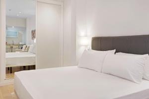 1 dormitorio con cama blanca y almohadas blancas en Apartamentos Metrópolis, en Sevilla