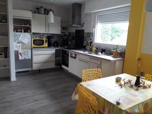 una cucina con tavolo da pranzo e una cucina con armadietti bianchi di La chambre Plume a Truchtersheim