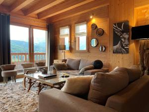a living room with a couch and a table at Chalet Alpaga Location de prestige in Manigod