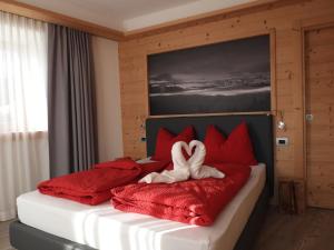 a bedroom with a bed with red pillows and a heart towel at Al Sole B&B Valcomelico in Santo Stefano di Cadore