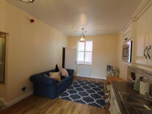 a living room with a blue couch and a kitchen at Garda House in Kinsale