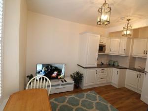 cocina con armarios blancos y TV de pantalla plana en Garda House, en Kinsale