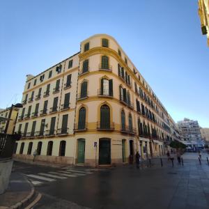 Un bâtiment jaune avec des gens debout devant lui dans l'établissement Vecino de Picasso, à Malaga