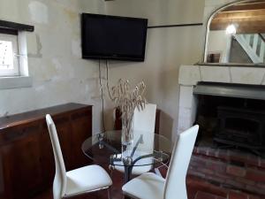 ein Esszimmer mit einem Glastisch und weißen Stühlen in der Unterkunft Cottage La Halouère in Saint-Philbert-du-Peuple