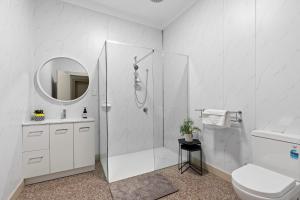 uma casa de banho branca com um chuveiro e um WC. em Loemans Lodge, 5 Bedrooms near Airport, Free Parking em Bulla