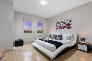Un dormitorio blanco con una gran cama blanca. en Loemans Lodge, 5 Bedrooms near Airport, Free Parking en Bulla