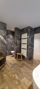 baño con paredes de mármol negro, bañera y lavamanos en BnB La Cravache en Rekkem