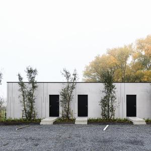 a white building with four doors in a parking lot at BnB La Cravache in Rekkem