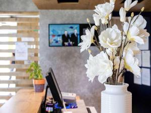 Ibis Budget Perpignan Nord Rivesaltes في ريفسالت: مزهرية مليئة بالورود البيضاء على المكتب