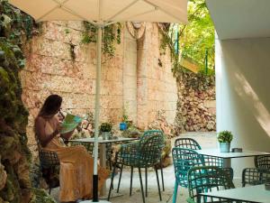 a woman sitting at a table under an umbrella at ibis Styles Golden Sands Roomer Hotel in Golden Sands