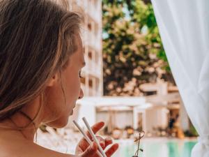a woman looking at a cigarette in her hand at ibis Styles Golden Sands Roomer Hotel in Golden Sands
