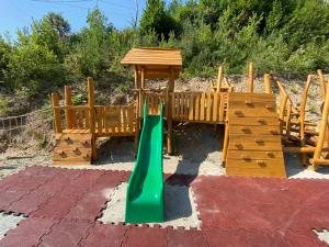 a playground with a green slide and a wooden playset at Apartmány Valča in Valča
