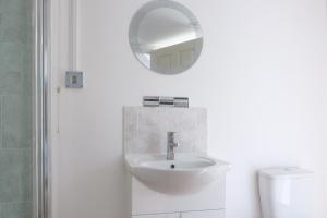 a white bathroom with a sink and a mirror at Dickens Suite- 15min close to Gatwick in Crawley